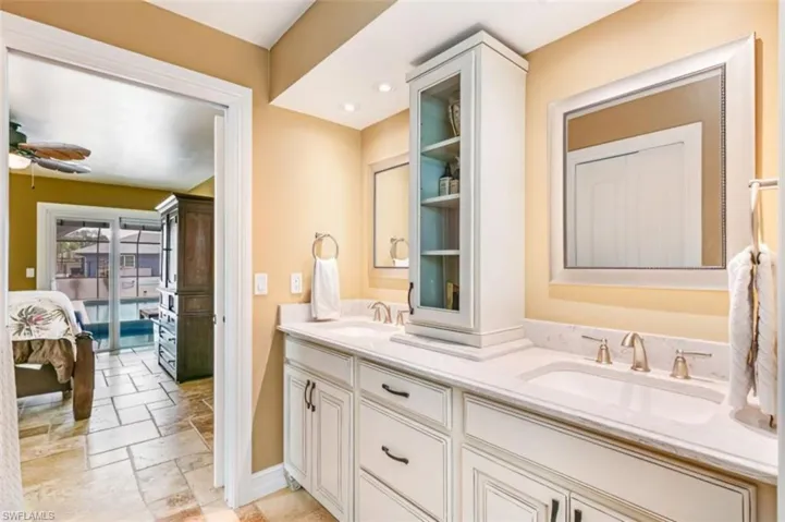 Ensuite bathroom with double vanity, ceiling fan, and stone tile floors - Virtually Edited Image