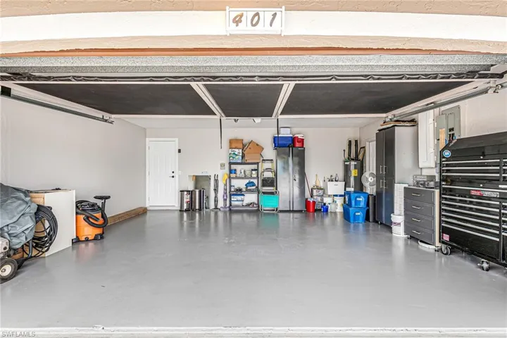 Garage featuring water heater and electric panel - Virtually Edited Image