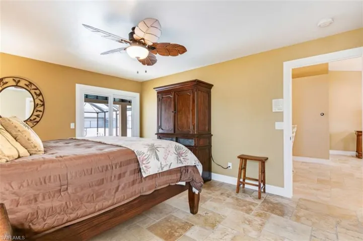 Bedroom with access to outside, ceiling fan, and stone tile flooring - Virtually Edited Image