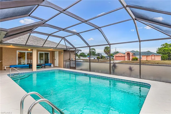 Outdoor pool featuring a sunroom, glass enclosure, and a patio area - Virtually Edited Image