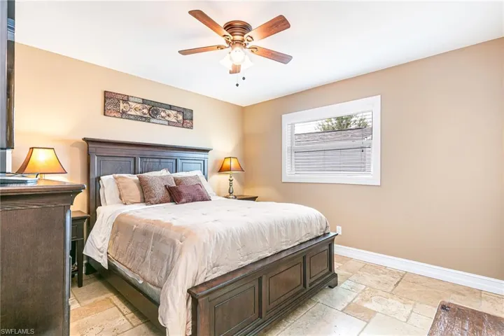 Bedroom with stone tile flooring and a ceiling fan - Virtually Edited Image