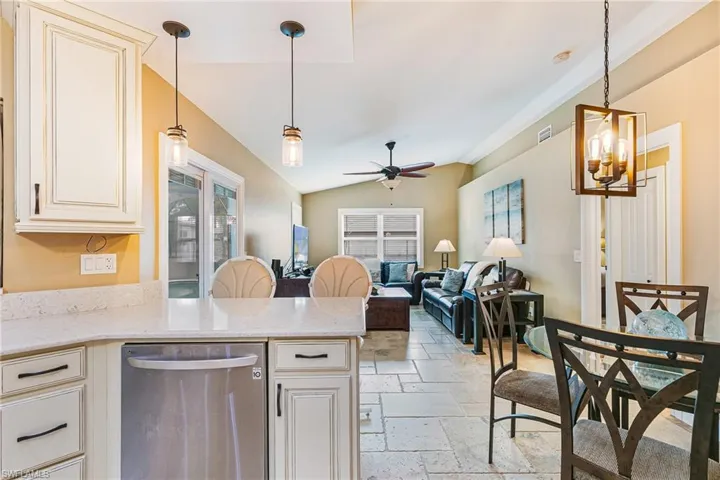 Kitchen featuring light stone  - Virtually Edited Imagecountertops, pendant lighting, cream cabinets, stone tile floors, and lofted ceiling