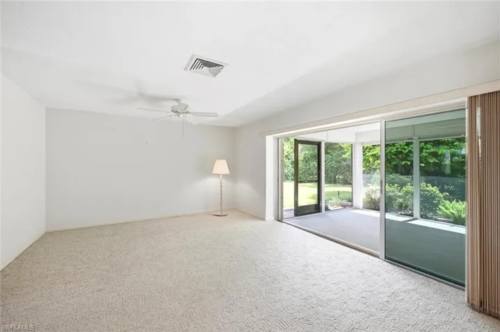 Carpeted interior space featuring white walls and a ceiling fan