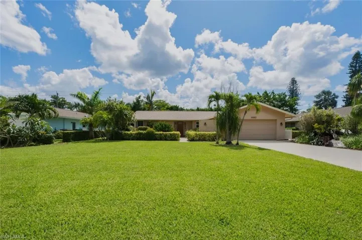 Expansive front lawn with mature landscaping and established palm trees