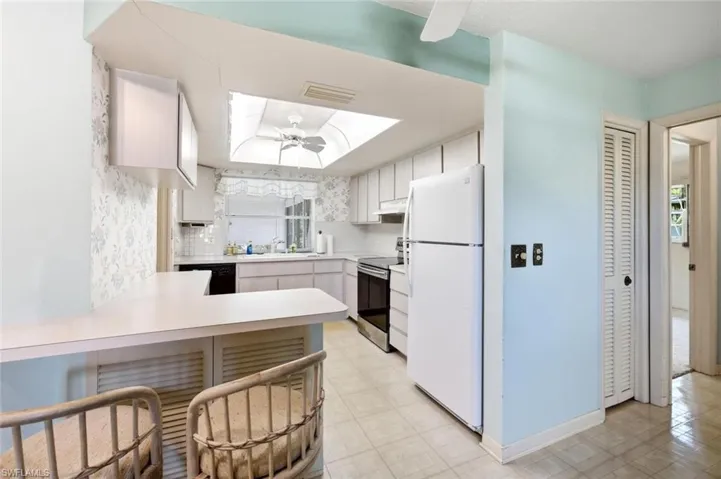Kitchen featuring a skylight, white cabinetry, black countertops, and a breakfast bar