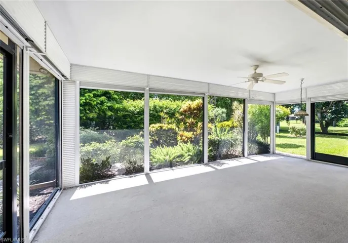 Spacious screened enclosure featuring ample natural light, a ceiling fan, a pendant light fixture, and a durable flooring surface