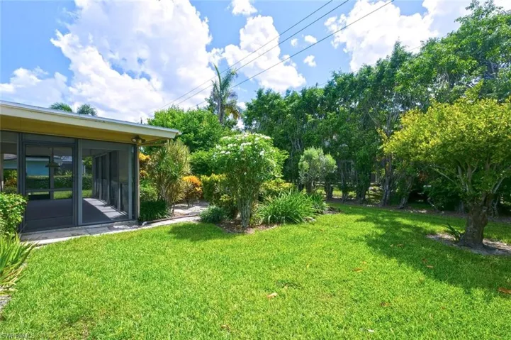 Screened patio with a concrete slab, overlooking a lush green lawn and mature landscaping