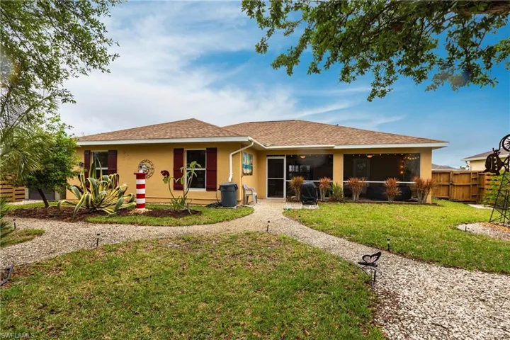 Rear view of property with a sunroom, a lawn, fence, stucco siding, and roof with shingles
