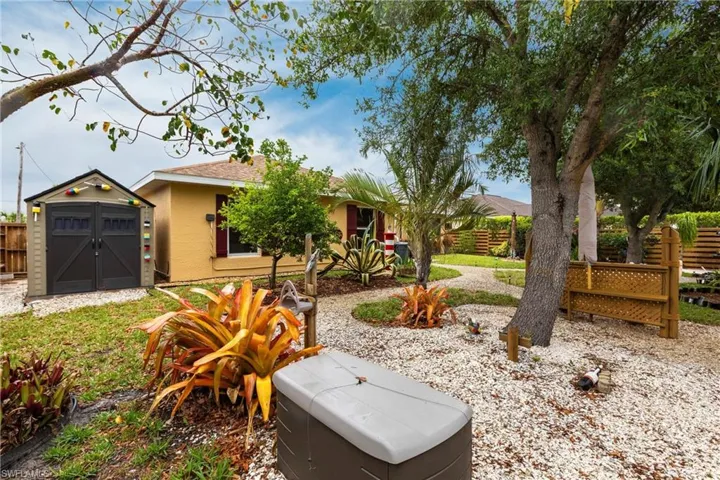 Ranch-style house with roof with shingles, stucco siding, an outdoor structure, a shed, and fence