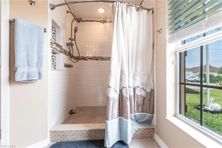 Bathroom featuring a tile shower and baseboards