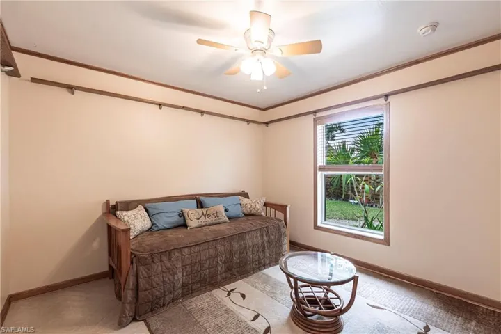 Bedroom with a trundel bed and ceiling fan, baseboards, and ornamental molding