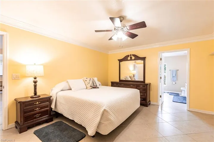 Bedroom featuring crown molding, light tile floors, and baseboards