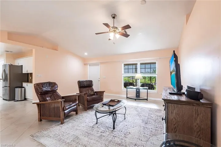 Living area with ceiling fan, baseboards, lofted ceiling, and light tile