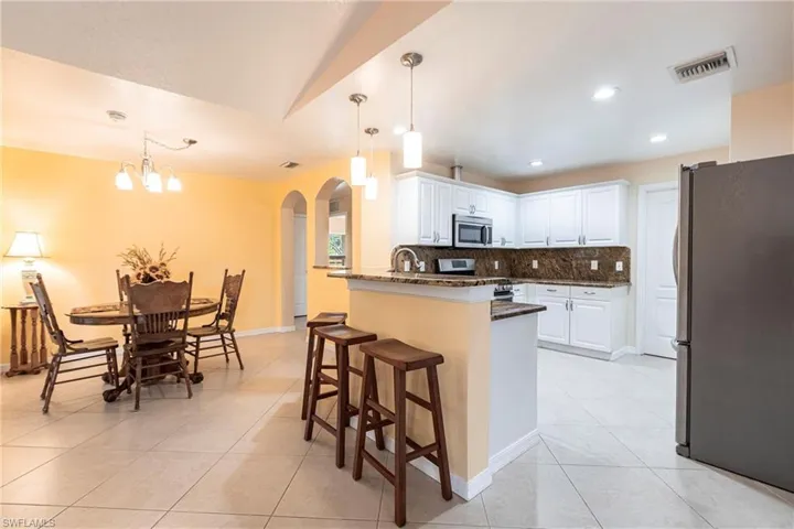 Kitchen with granite countertops, a peninsula, appliances with stainless steel finishes, and arched walkways