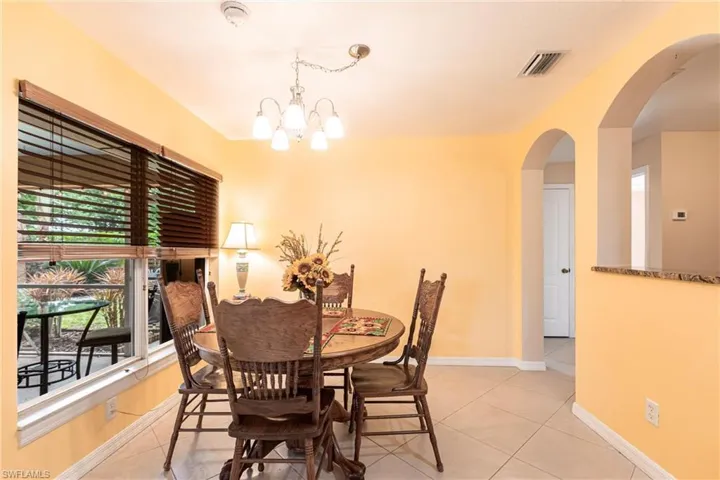 Dining space with baseboards, an inviting chandelier, light tile floors and arched walkways
