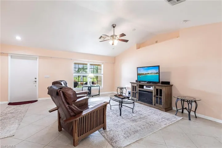 Living area featuring baseboards, vaulted ceiling, a ceiling fan, and light tile