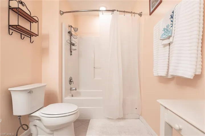 Full bathroom featuring toilet, baseboards, tile flooring, and shower / tub combo with curtain