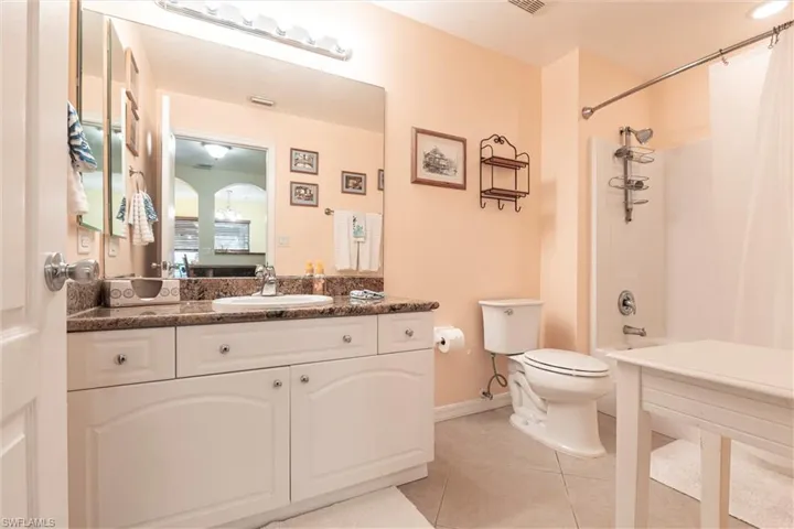 Bathroom with shower / tub combo, baseboards, toilet, vanity, and tile patterned flooring