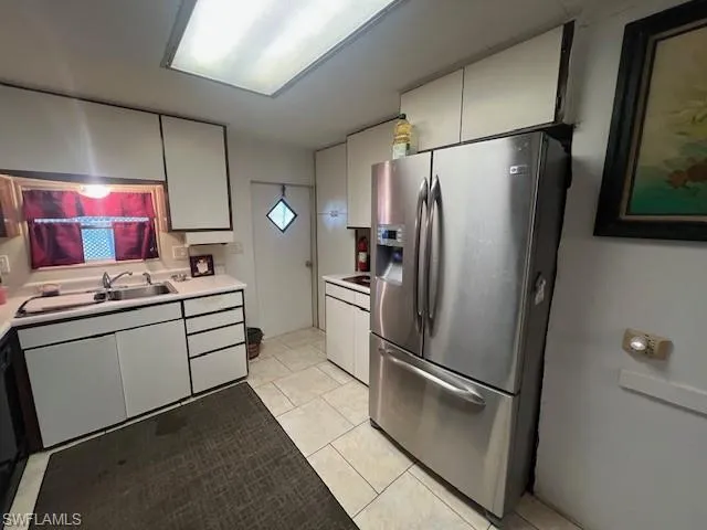 Kitchen with stainless steel fridge with ice dispenser, light countertops, light tile patterned flooring, and white cabinetry