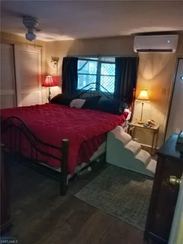 Bedroom with wood finished floors and a wall mounted air conditioner
