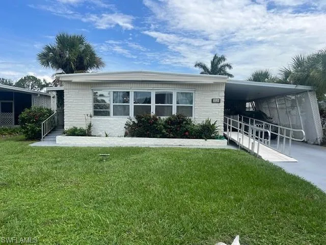Manufactured / mobile home with a carport, a front lawn, driveway, and brick siding