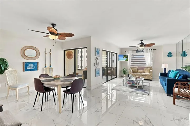 Open-concept living and dining areas featuring large format white tile flooring, ceiling fans, and sliding glass doors with vertical blinds - Virtually Edited Image