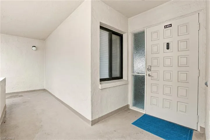 Recessed entry with textured walls, concrete flooring, and an exterior light fixture - Virtually Edited Image