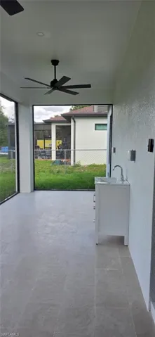 Screened lanai featuring large ceiling fan and sink