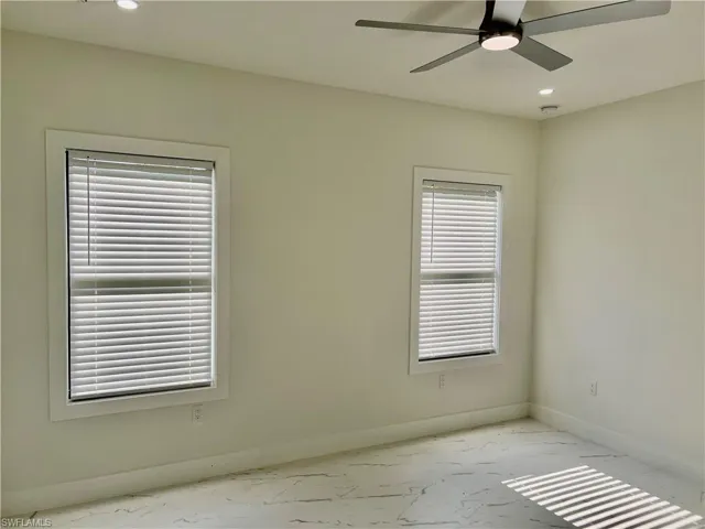 Bright room featuring two windows with blinds, a ceiling fan, recessed lighting, and patterned tile flooring