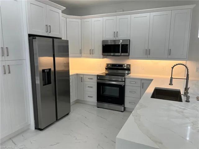 Contemporary kitchen featuring white shaker cabinetry, stainless steel appliances, and sleek countertops