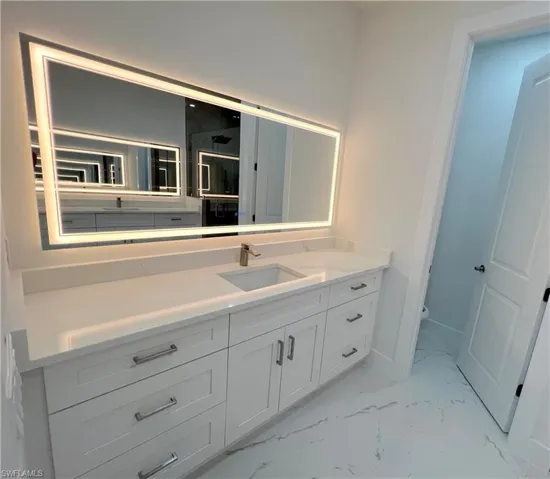 Full bath with vanity and light marble finish flooring