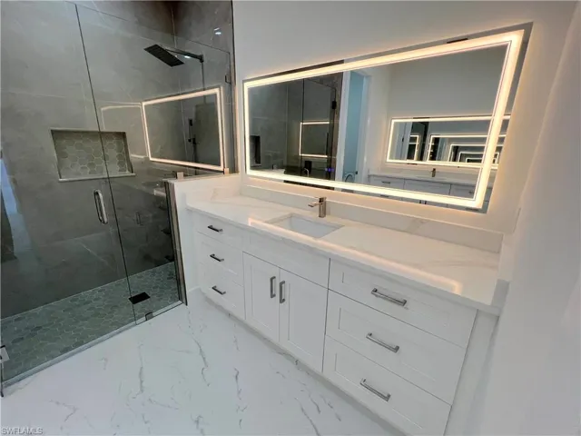 Bathroom with a marble finish shower and vanity