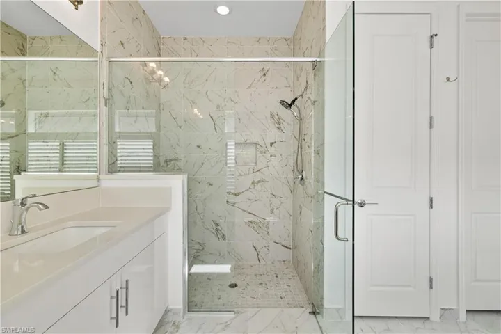 Shower enclosed with a clear glass door and tiled all the way to the ceiling.