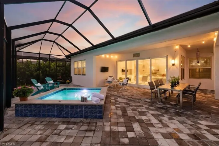 Screened outdoor area featuring a spool, a spacious paver patio, and a covered dining area with string lighting