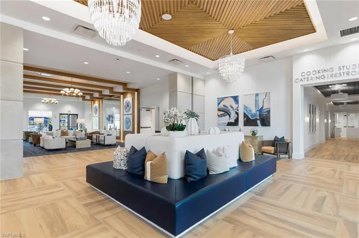 Beautiful and spacious community center common area featuring light-toned wood-finish flooring, a wood-paneled ceiling, and multiple crystal-style chandeliers