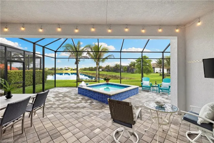 Screened lanai featuring a paver patio and a built-in spool with blue tile surround