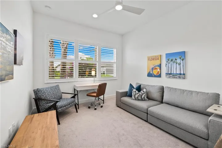 Large guest bedroom featuring a multi-pane window with white plantation shutters, a sleek ceiling fan, recessed lighting, and soft carpet flooring