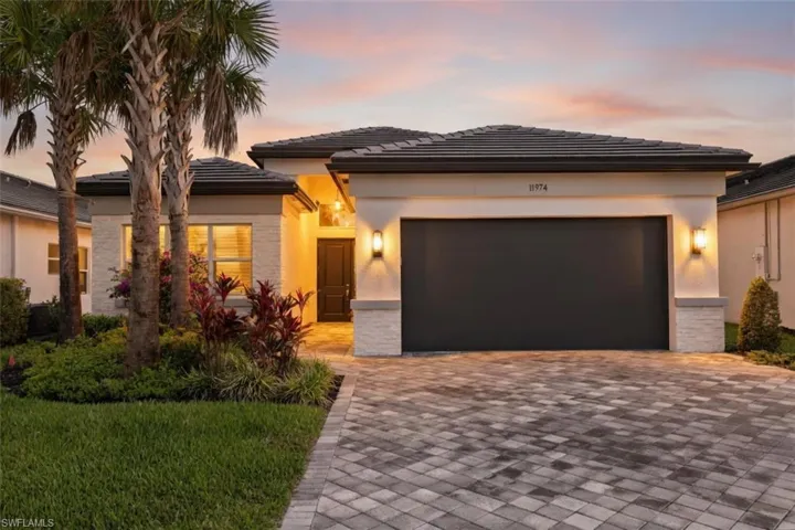 Contemporary stucco exterior with tile roof, paver driveway, and accent stone veneer