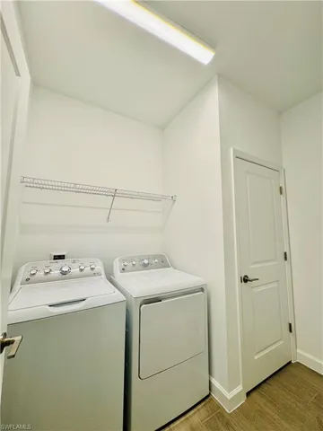 Laundry room with wood finished floors and independent washer and dryer