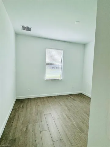 Unfurnished room featuring light wood finished floors and baseboards
