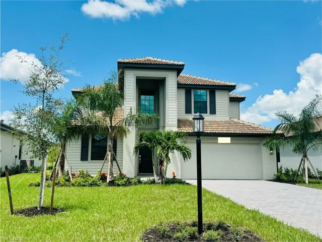 View of front of property featuring a tiled roof, a front yard, decorative driveway, and an attached garage