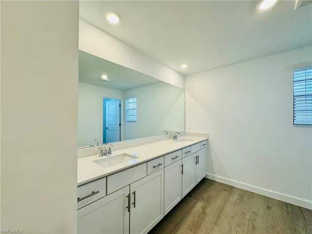 Full bath with light wood-type flooring and double vanity