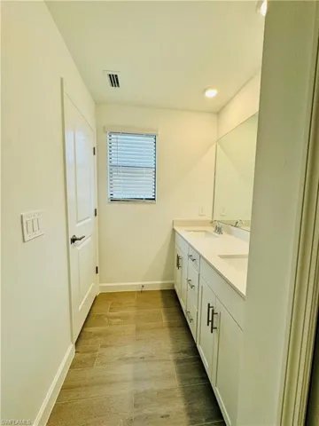 Full bathroom with double vanity, wood finish floors, and recessed lighting