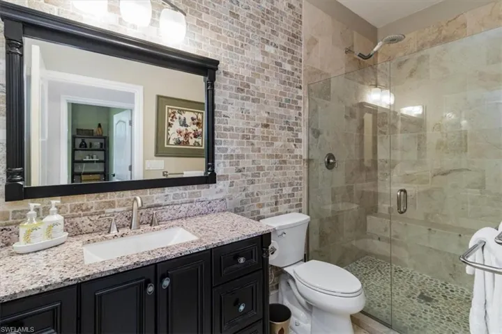 Guest Bathroom with vanity, tile walls, decorative backsplash, toilet, and a shower with door