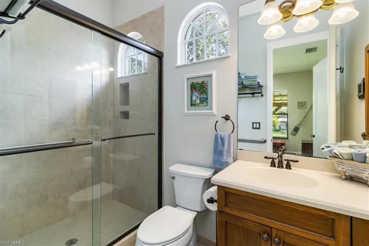In-Law Bathroom with a chandelier, a shower with shower door, toilet, and vanity