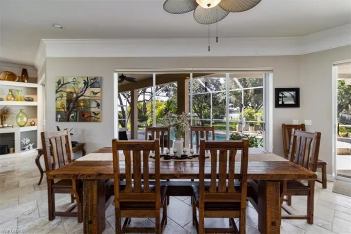 Dining room with light tile patterned flooring, built in shelves, ornamental molding, and ceiling fan