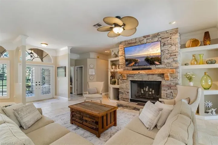 Living room with ceiling fan, crown molding, a fireplace, and French doors