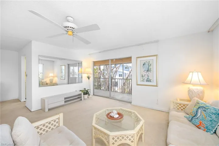 Living room with carpet floors, a ceiling fan, and baseboards