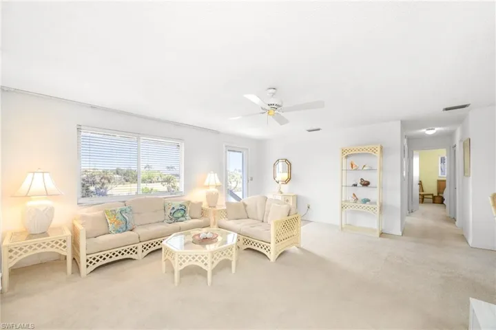 Living area with a ceiling fan, visible vents, and carpet