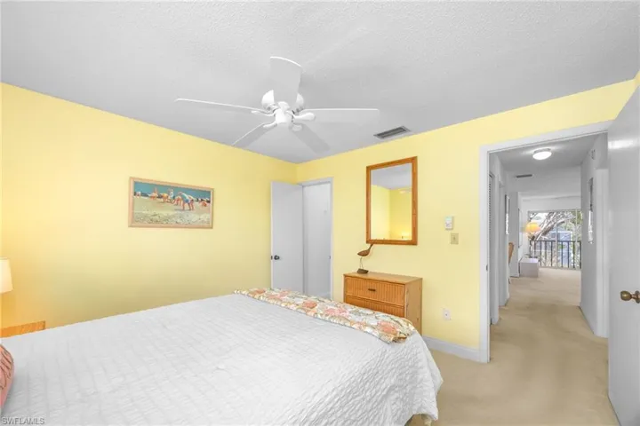 Bedroom with light carpet, a textured ceiling, baseboards, visible vents, and ceiling fan